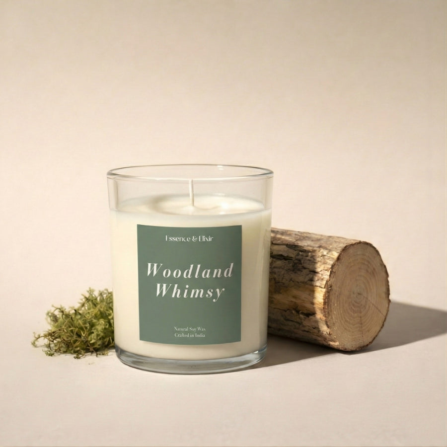 Candle labeled 'Woodland Whimsy' with a log and plant on a beige background